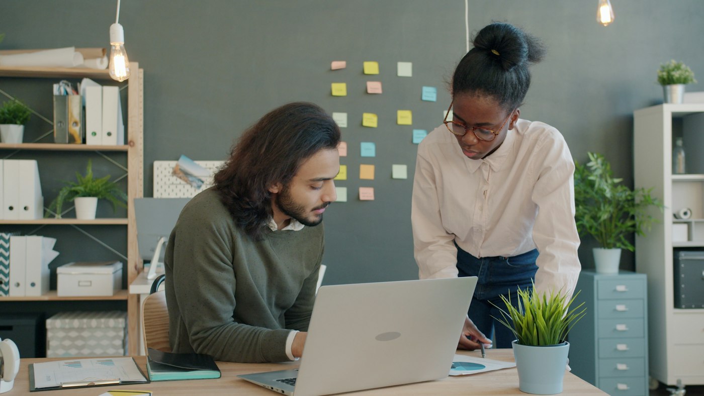 Two colleagues working together at a desk in a modern office