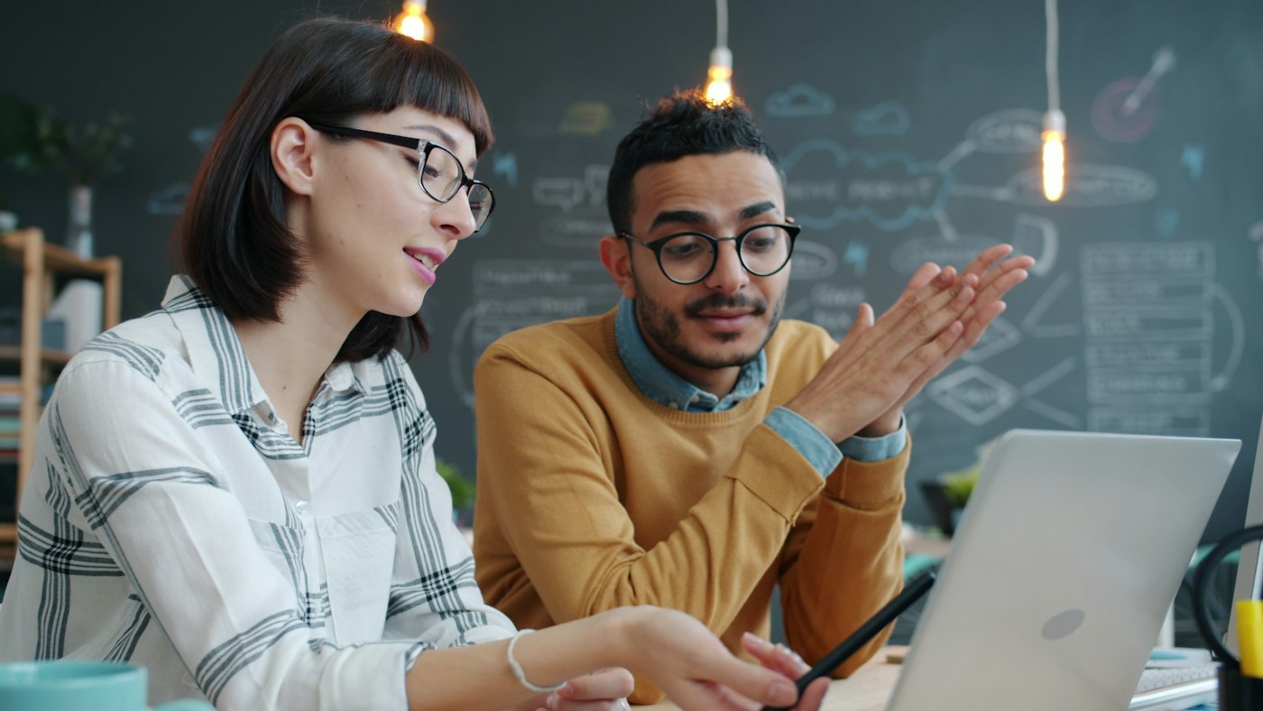 Two colleagues working through a problem together at a laptop